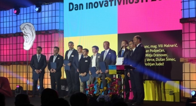 A group of award winners are standing on the podium and posing for a photograph at the 16th Innovation Day of the Chamber of Commerece and Industry of Slovenia (GZS)