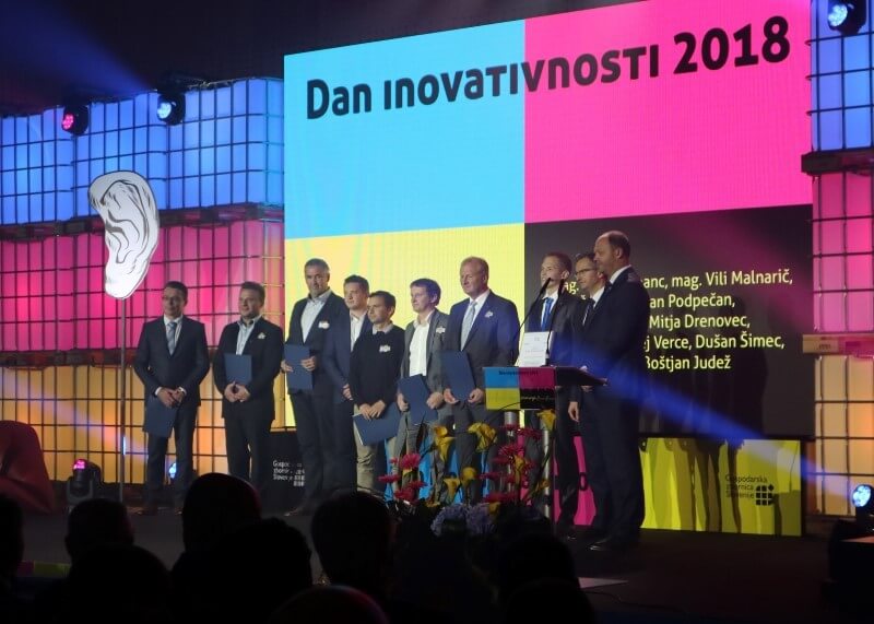 A group of award winners are standing on the podium and posing for a photograph at the 16th Innovation Day of the Chamber of Commerece and Industry of Slovenia (GZS)